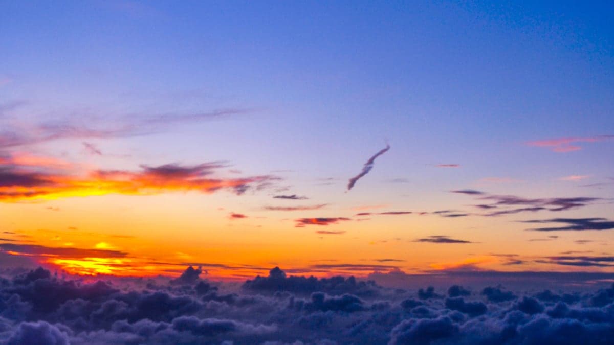 Flugzeugflügel über dem Wolkenmeer bei Sonnenuntergang, unterwegs zu den Beschaffungsmärkten in Fernost